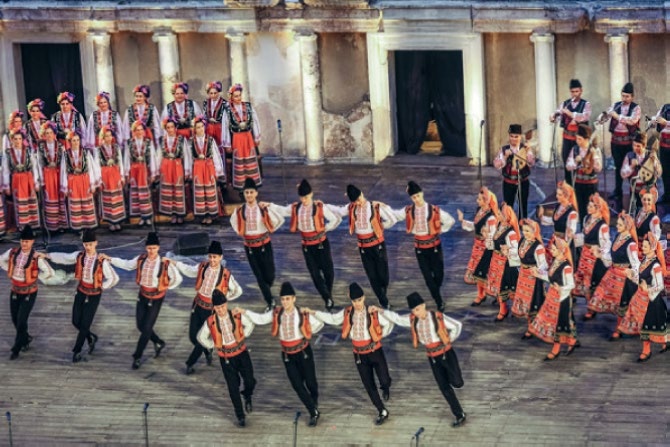 Bulgarian folk dancers perform traditional dances characterized by complex "aksak" rhythms with uneven beats.